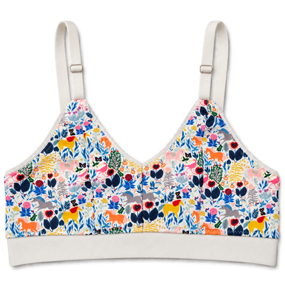 SWOOP wireless bra with adjustable shoulder straps and a white band, featuring a vibrant multicolor unicorn and floral print on a white base, shown against a plain white background.